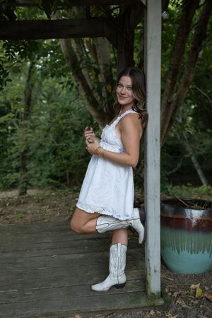 Fashion portraits on a wooden deck featuring white cowboy boots and delicate summer dress.
