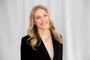 Professional headshot portrait of someone in business attire against a light gray background.