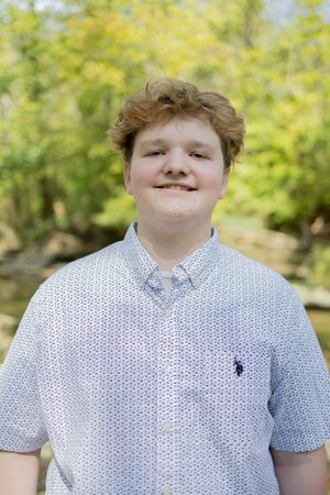 Portrait of youth in white patterned shirt against sunny natural background.