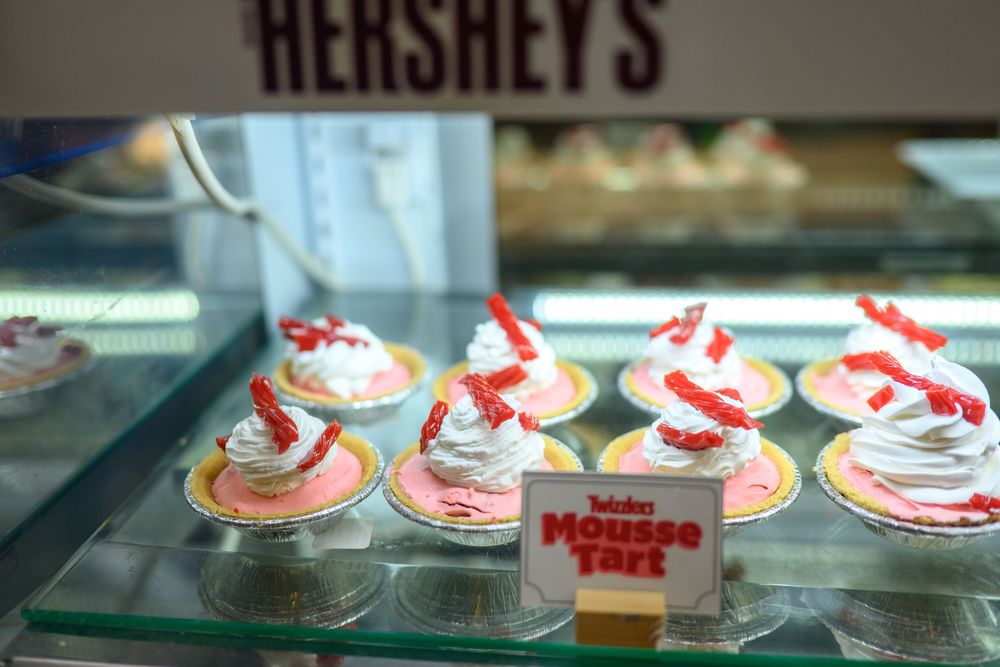 An assortment of red and white frosted cupcakes in a bakery display case with decorative toppings.