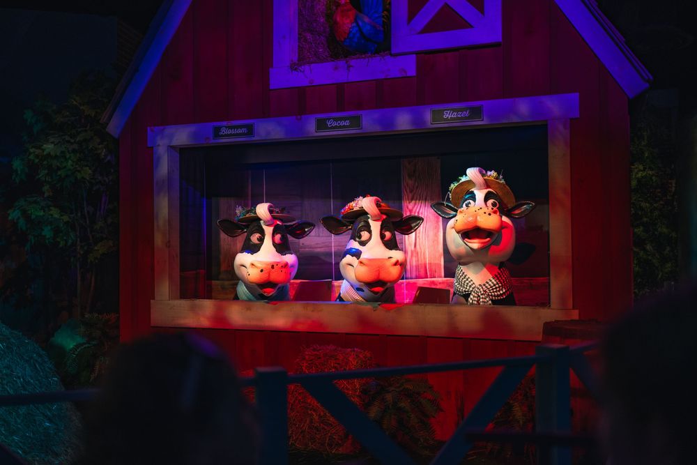 Animatronic animals perform a musical show in a colorfully lit barn-style theater setting.