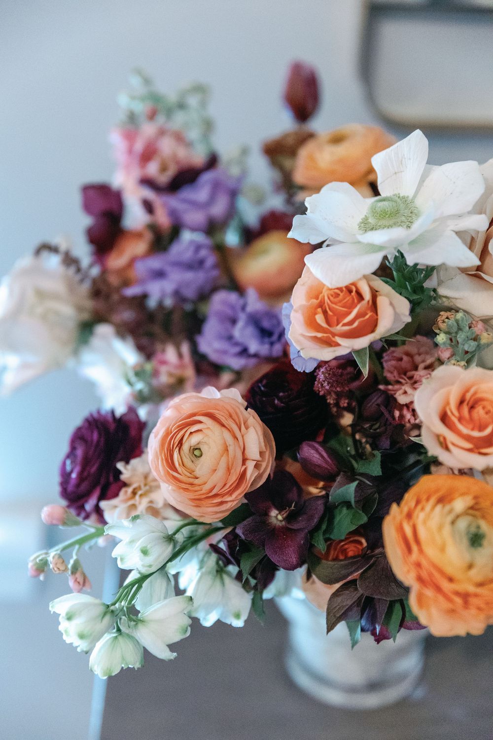 Beautiful floral arrangements featuring peach roses, purple blooms and white flowers in small vases.