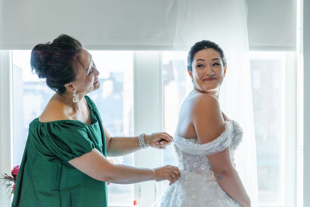 Wedding preparation scene with a bride in a white gown getting dressed.