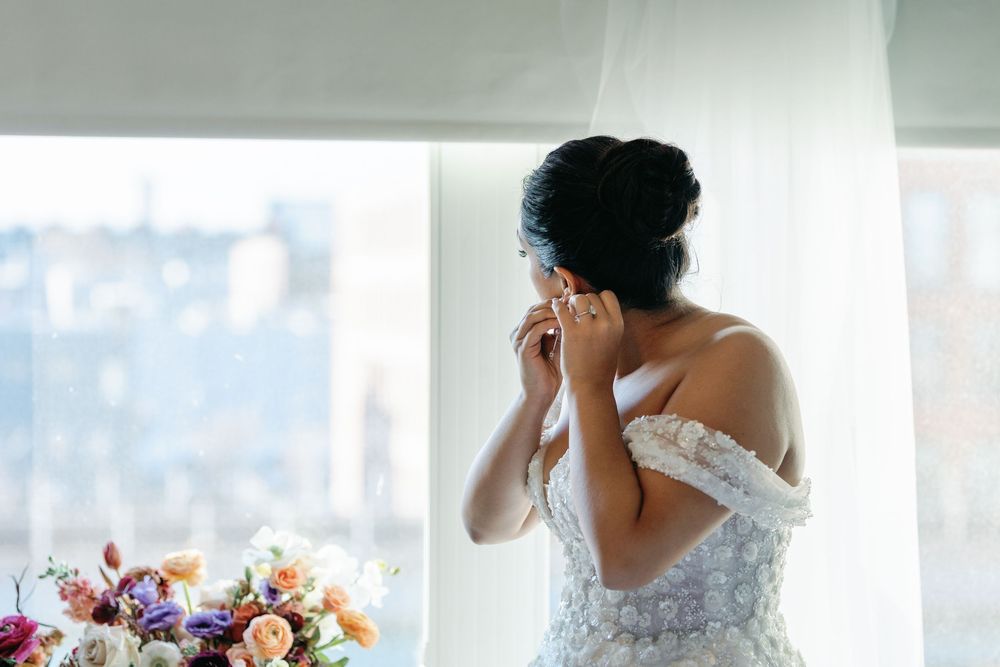 An emotional moment captured near a window with a bridal bouquet in the foreground.