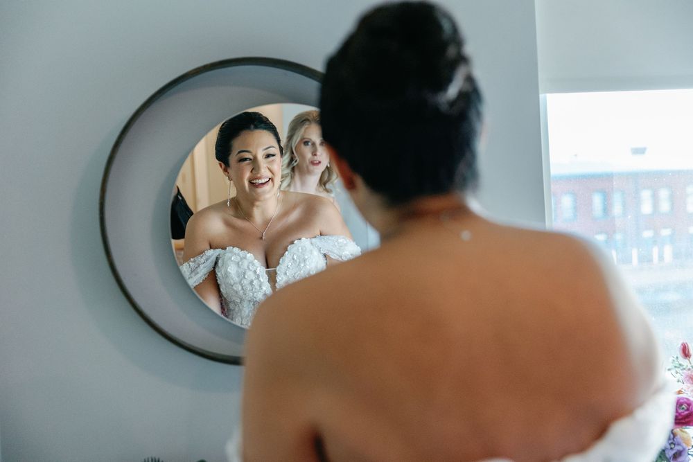Mirror reflection shows bride getting ready on wedding day.