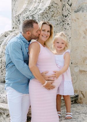 A tender family moment captured against a weathered stone wall.