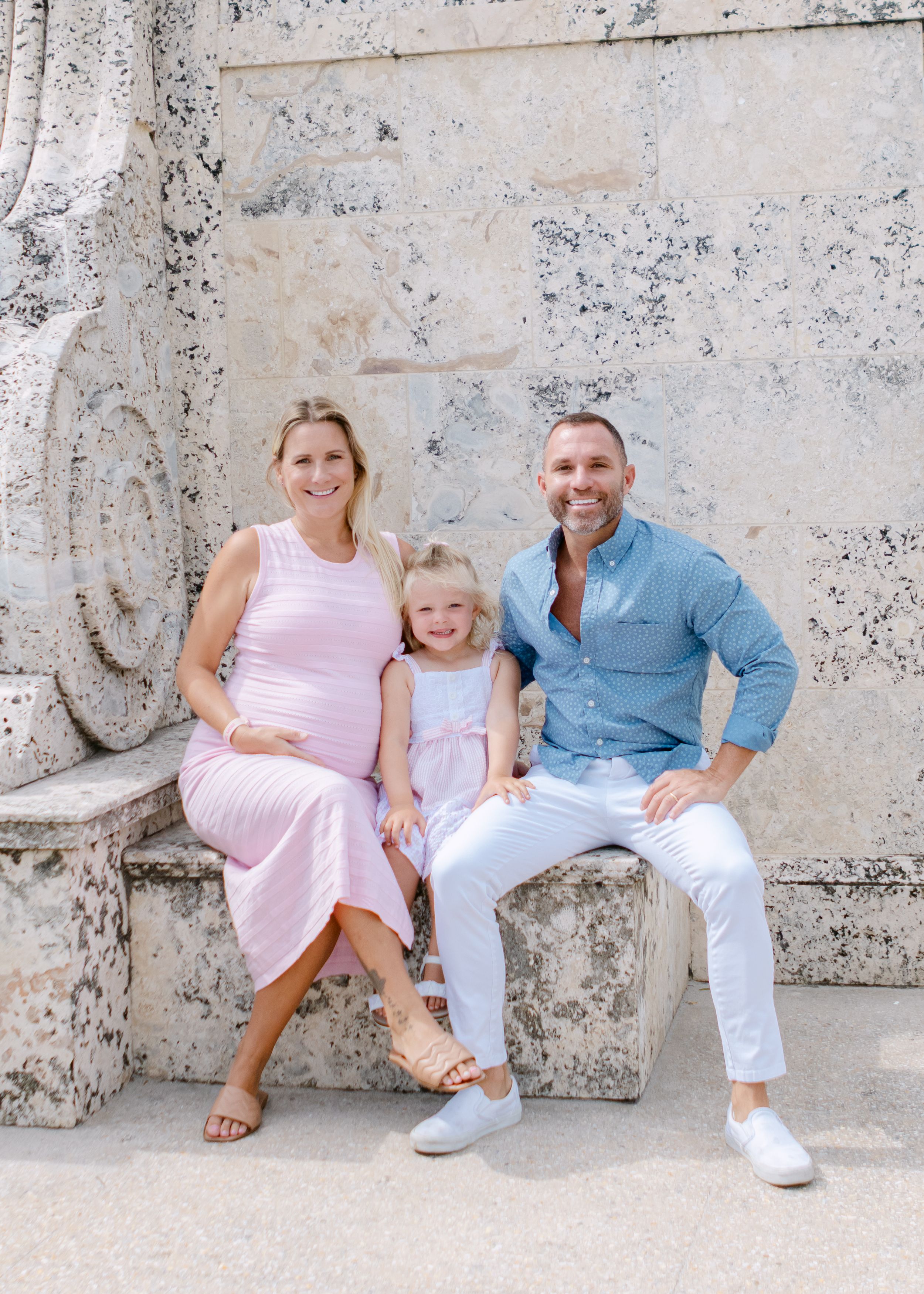 A family sitting together on stone steps wearing coordinated blue and pink outfits.