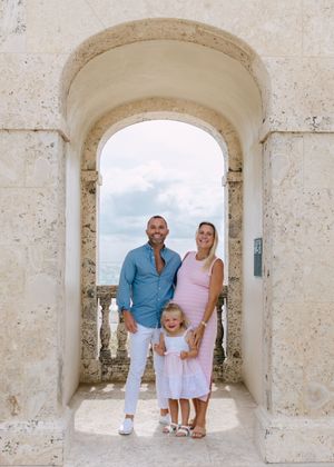 A family poses under stone archways at a historic location.