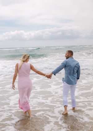 A family holding hands while walking through ocean waves.