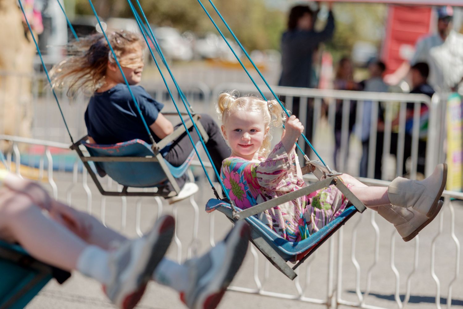 Children enjoying a carnival swing ride on a sunny day.