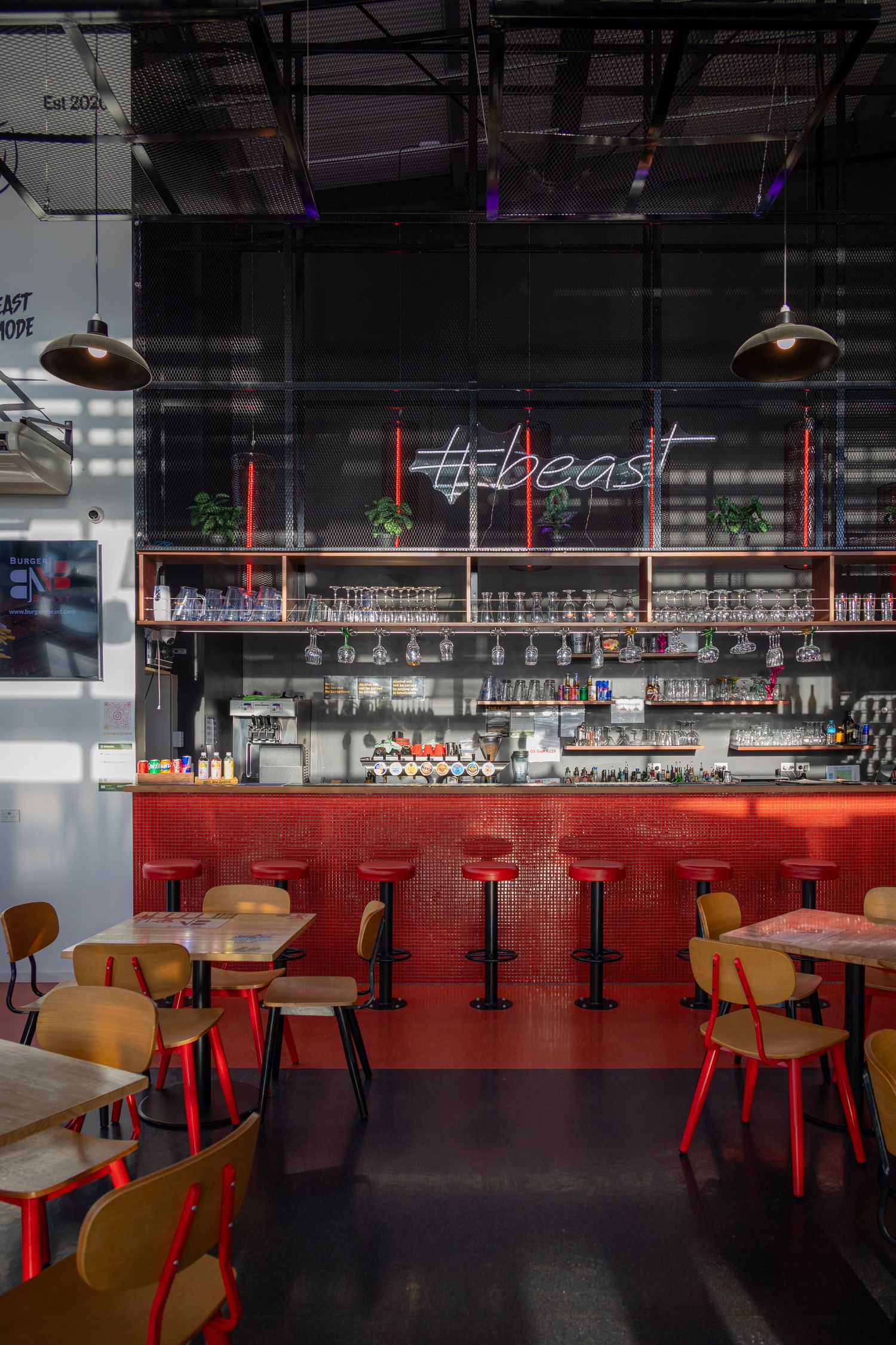 Bold red-and-black bar interior with playful lighting and a neon "# Beast" sign above.