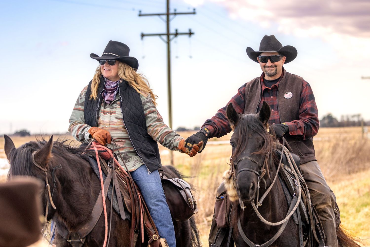 Cowboys riding horses across a scenic autumn field during sunset.