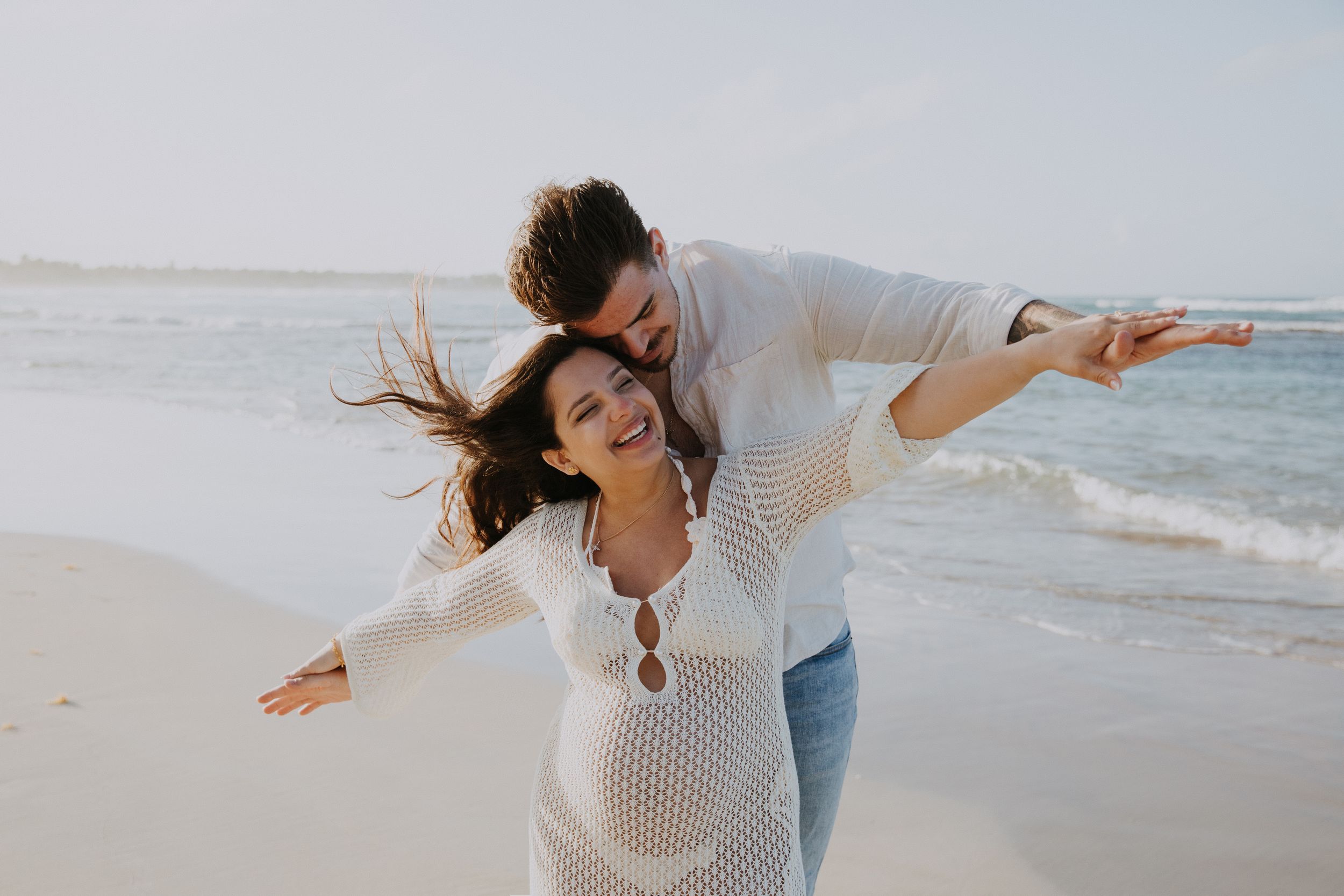 Playful beach photography session with couple running and laughing along the shoreline.
