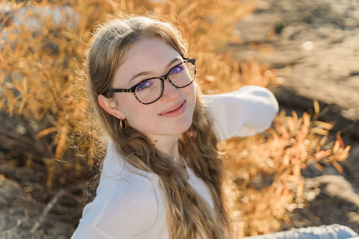 Perrysburg High School senior smiles warmly while sitting outdoors among autumn foliage at Side Cut Metropark.