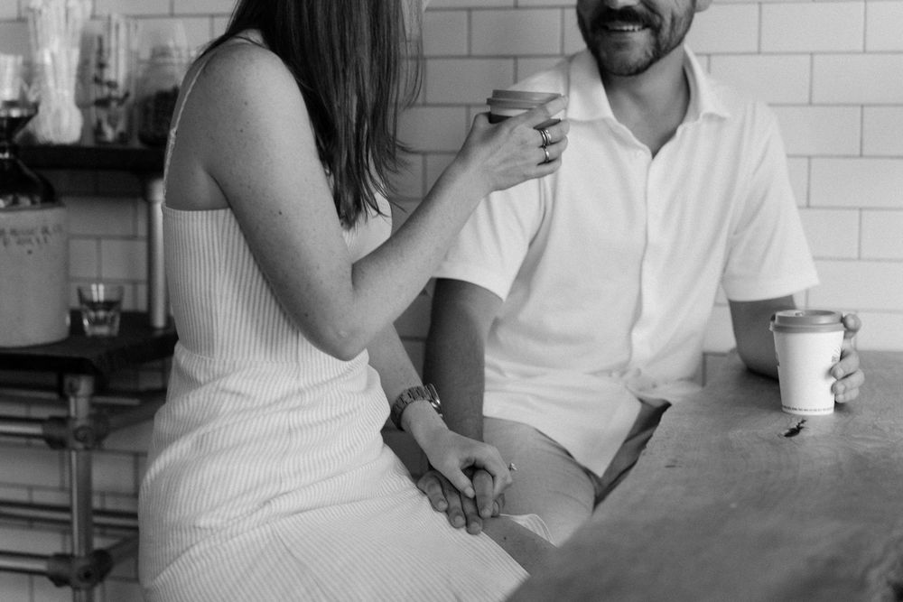 A couple shares an intimate moment at a white-tiled counter in casual attire.