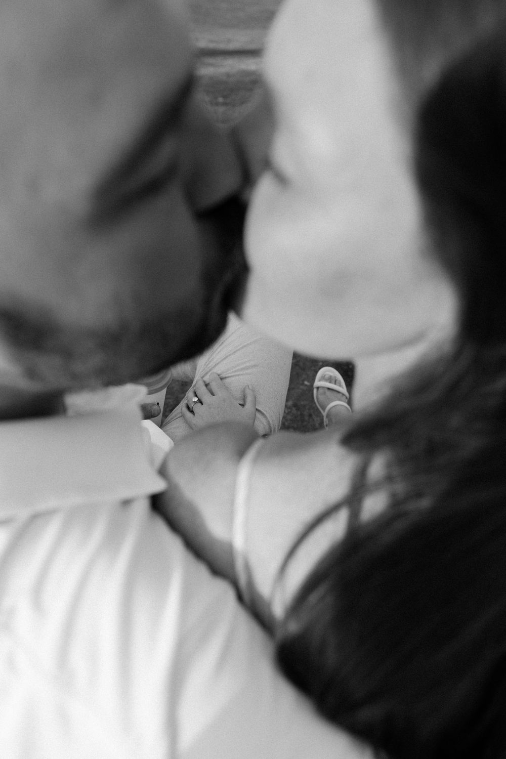 Black and white close-up shows two pairs of shoes touching in an intimate moment.