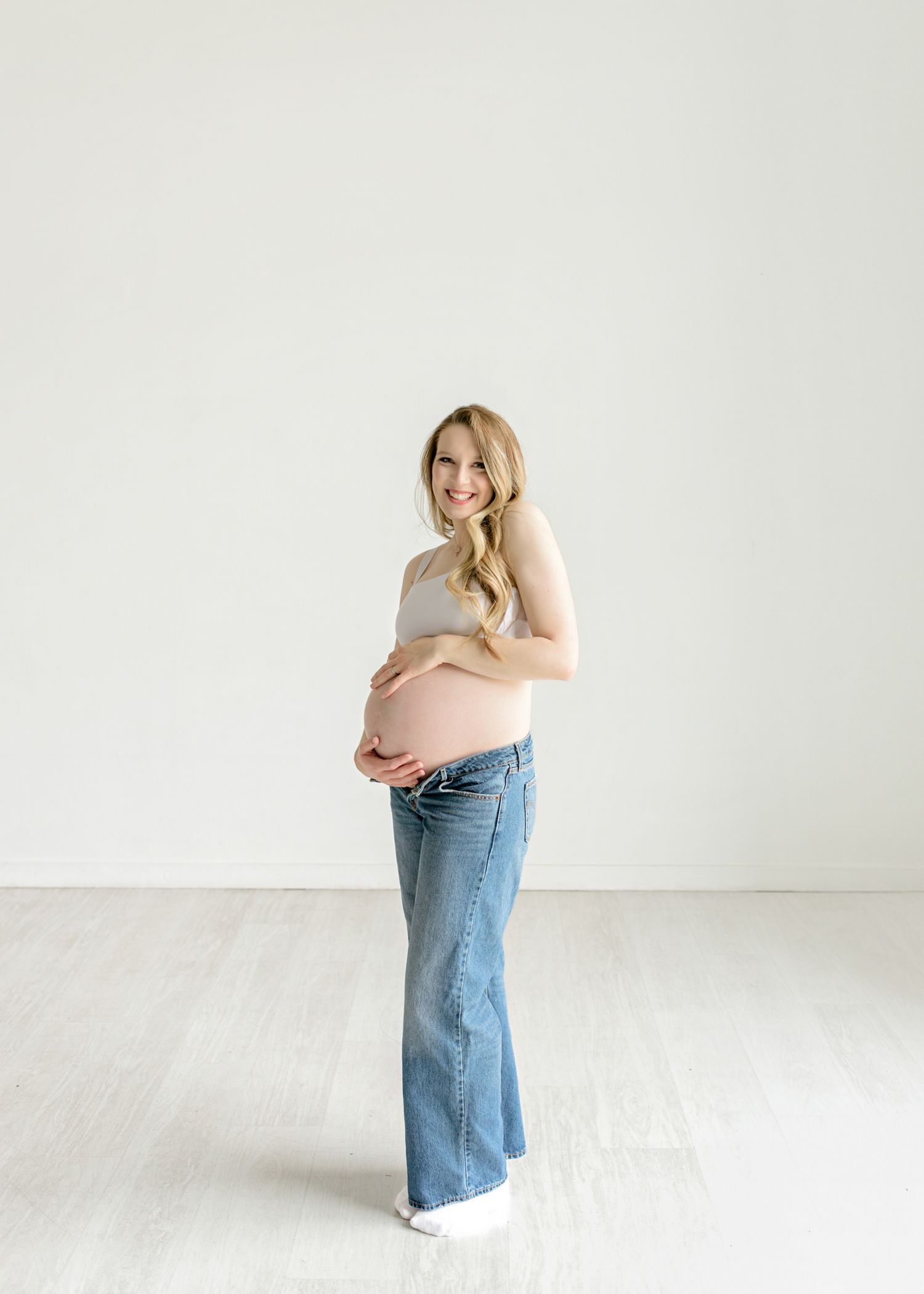 A woman wearing a peach colored top and wide leg jeans poses against a white background in four different stances.