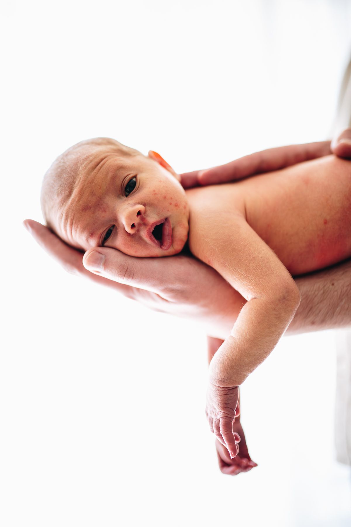 A serene portrait showing a newborn peacefully lying down on father's arm in soft lighting taken by Melbourne newborn photographer.