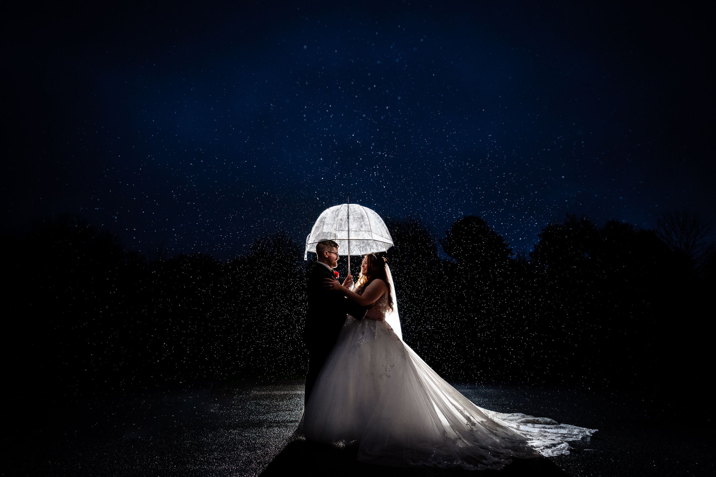 Dramatic nighttime wedding portrait with creative lighting and silhouettes.