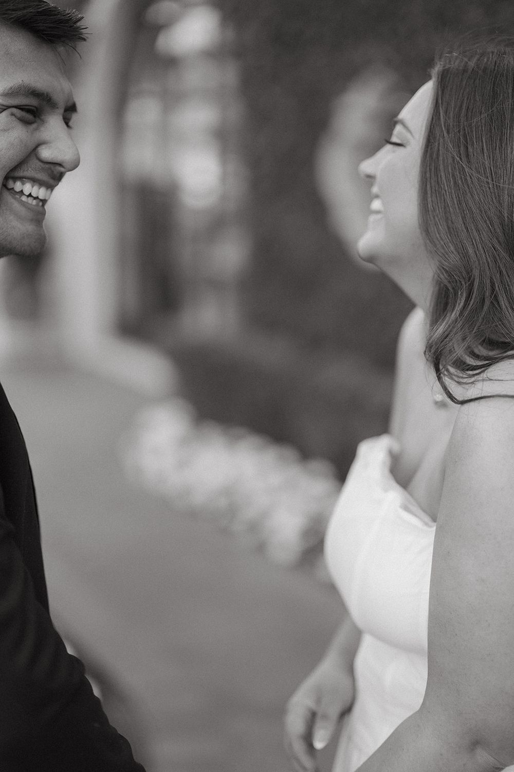A joyful moment captured in black and white as a couple shares laughter during their wedding day.