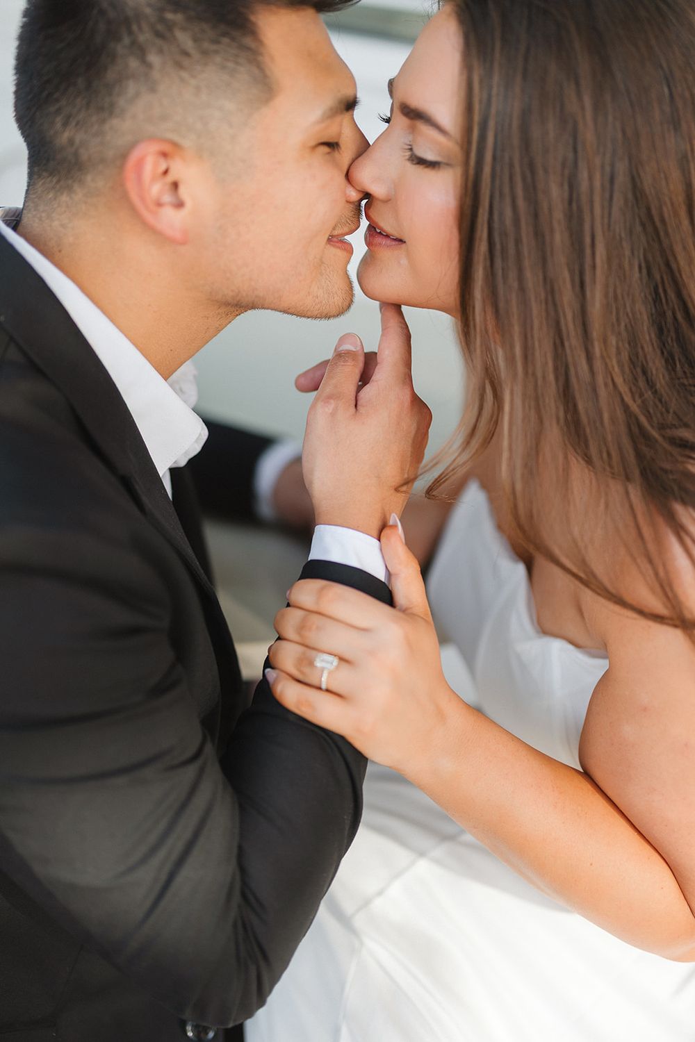 A tender romantic moment captured between a couple in wedding attire with soft lighting and gentle intimacy.
