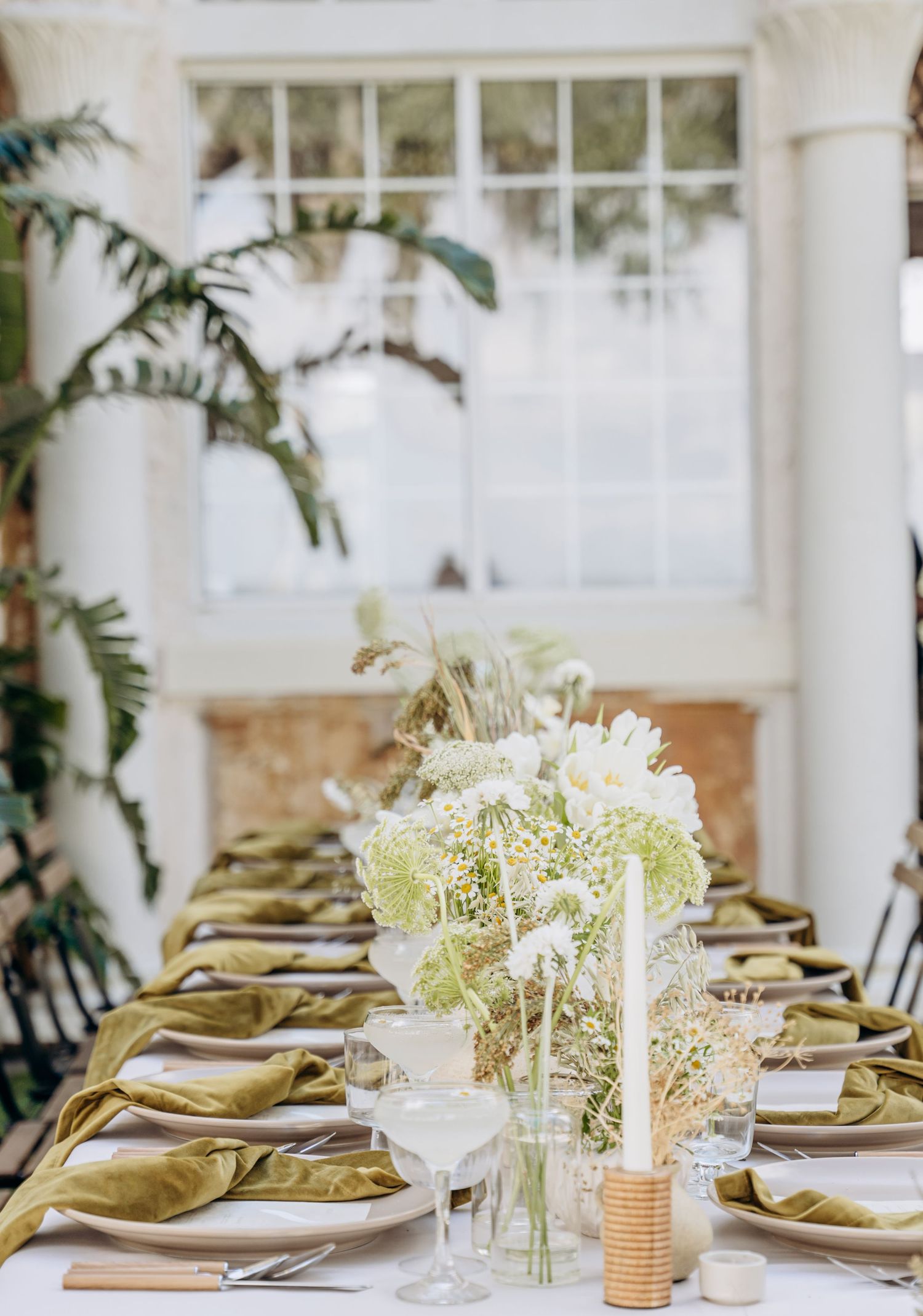 Close-up of wedding table settings with white tablecloths, gold accents, and fresh floral arrangements.