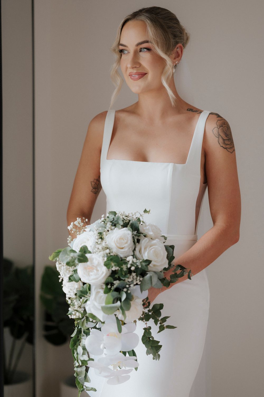 Elegant white bridal bouquet with roses and eucalyptus leaves.