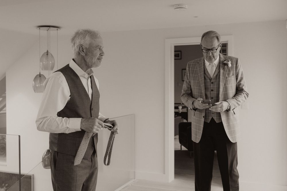 A sequence of black and white photos showing someone adjusting formal attire against a white wall.