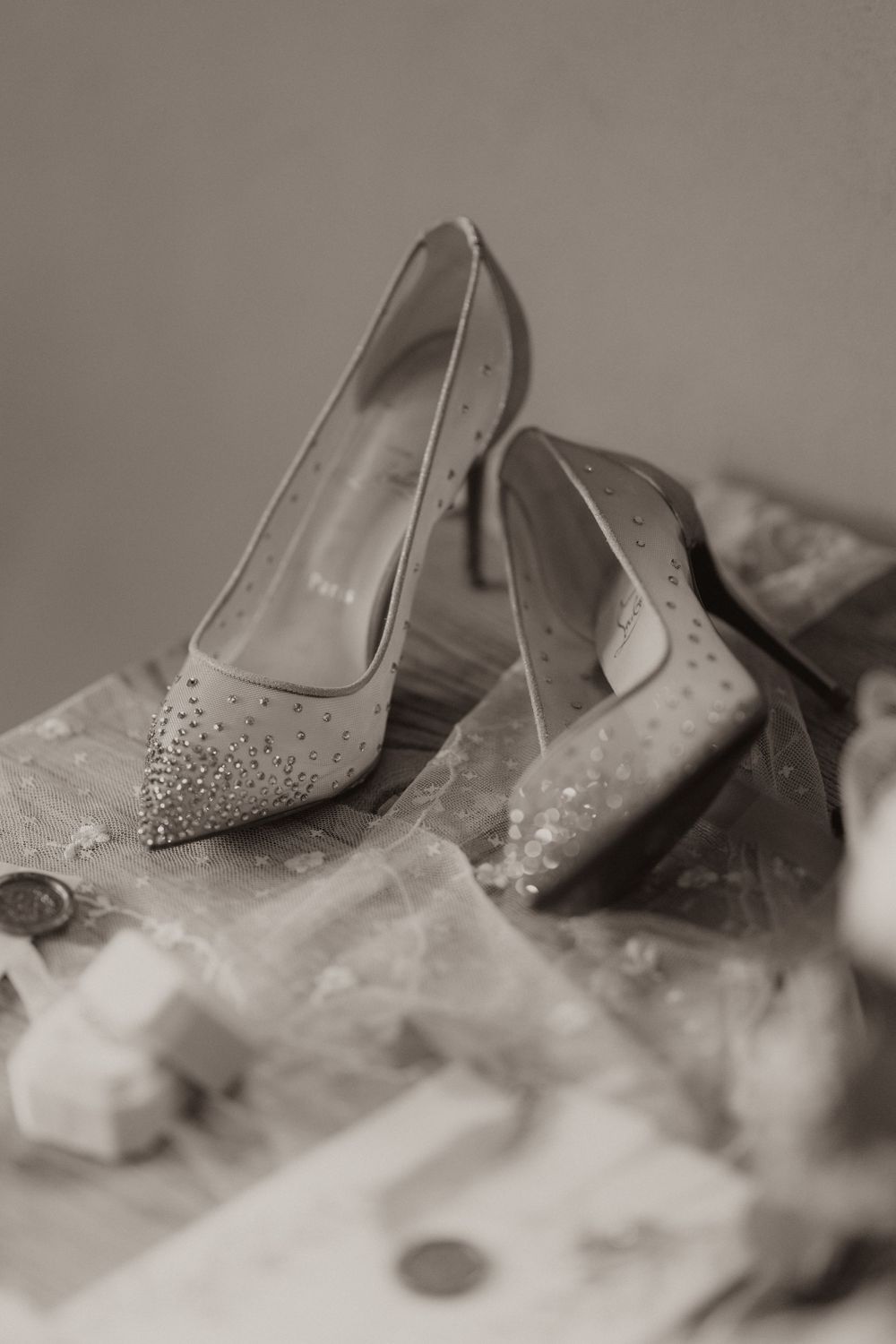 Elegant sparkly pointed-toe bridal shoes in a vintage black and white photograph.