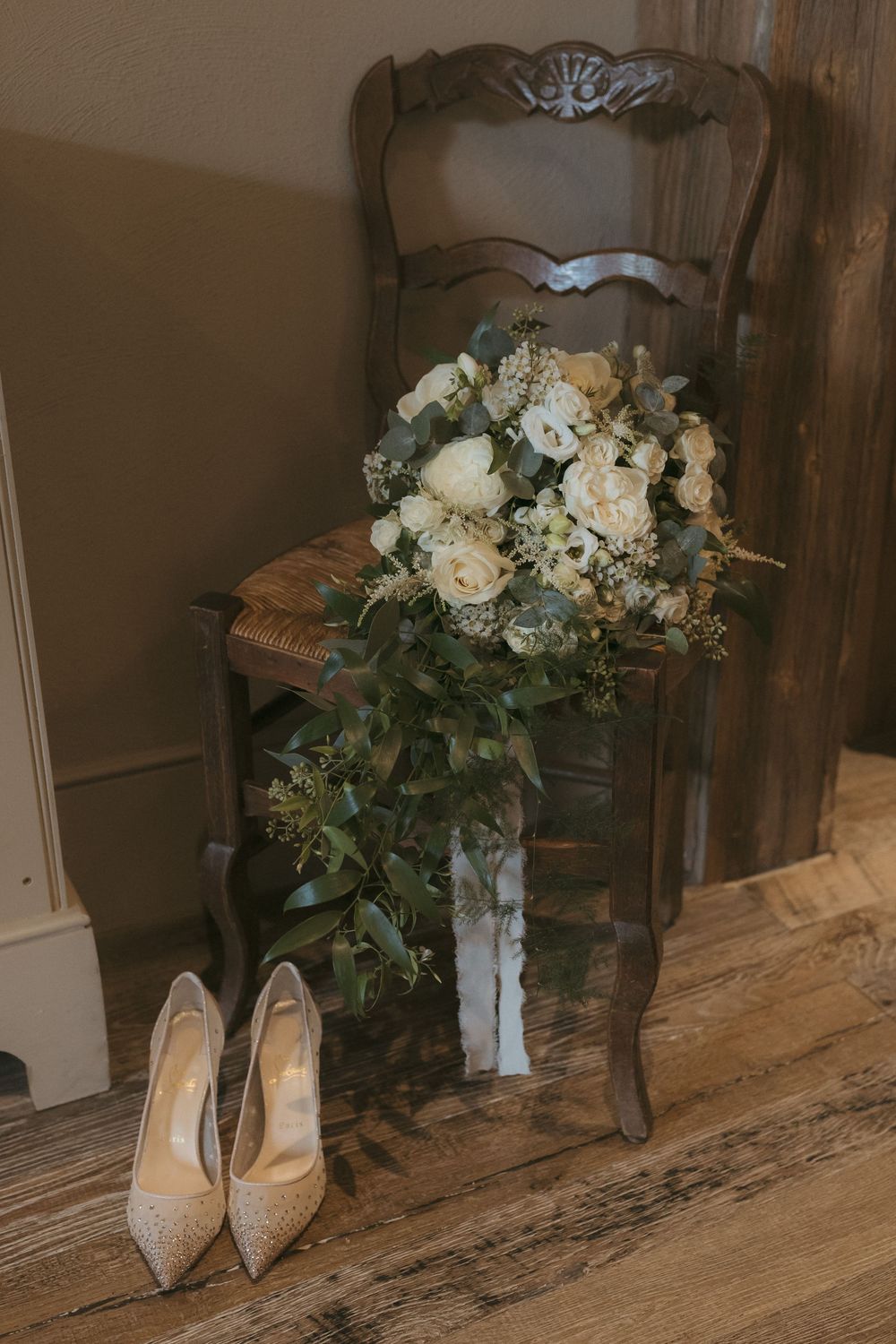 Elegant bridal shoes and wedding bouquets displayed on rustic wooden floorboards.