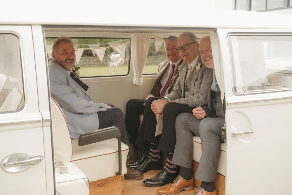 Wedding guests seated inside a classic vintage white vehicle.