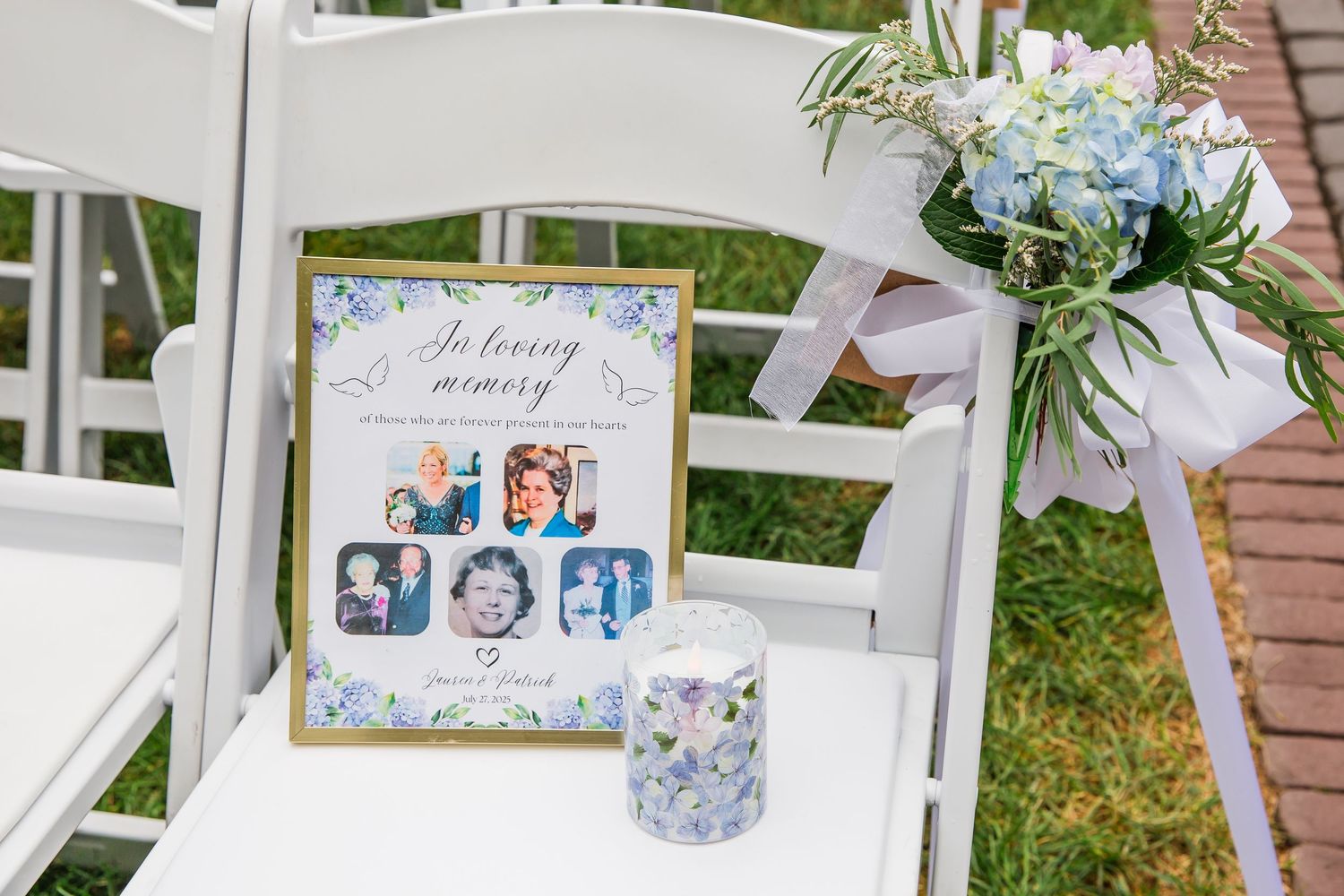 White wooden signs with handwritten names and messages stand displayed in grass at an outdoor wedding ceremony setup.