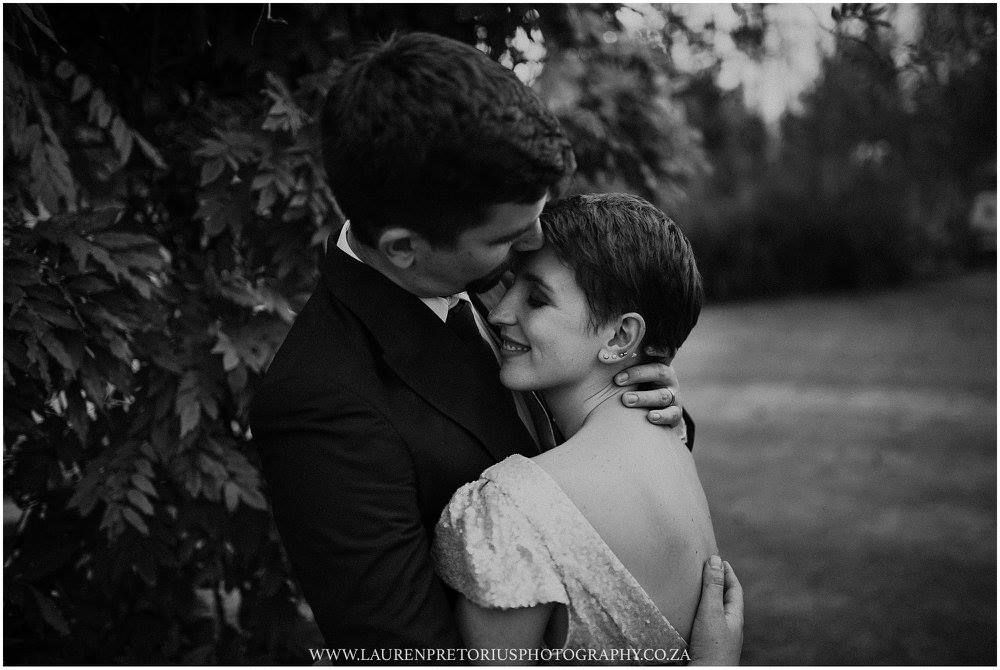 An intimate black and white wedding portrait capturing a tender embrace between newlyweds.