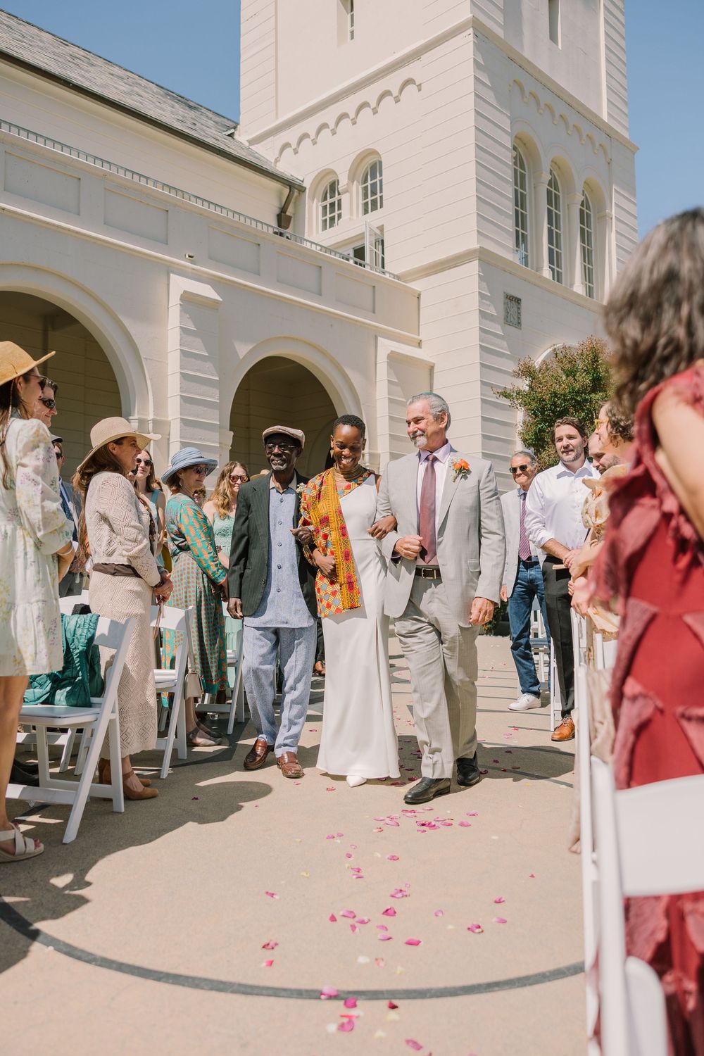 Bride and father of the bride and father walk out from under the arches at Geneva Terrace as guests cheer and toss confetti.