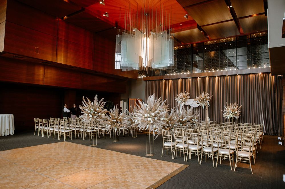 Modern wedding reception venue with dramatic white floral installations and silver chiavari chairs in an elegant ballroom setup.