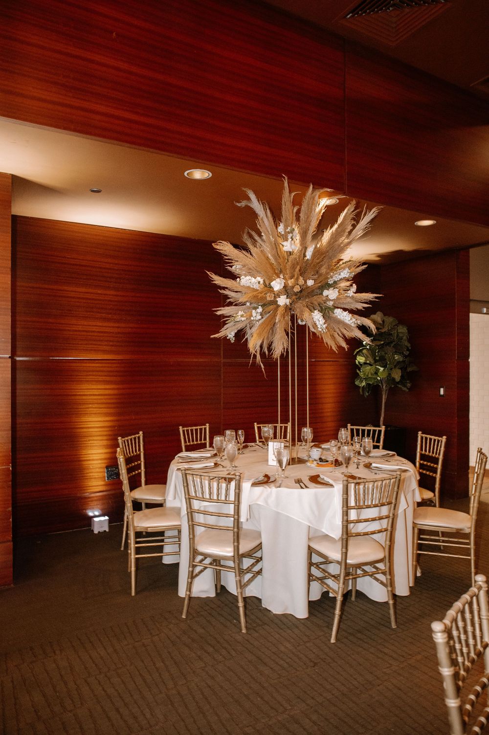 Elegant wedding reception space with white chiavari chairs and dramatic starburst centerpieces on round tables.