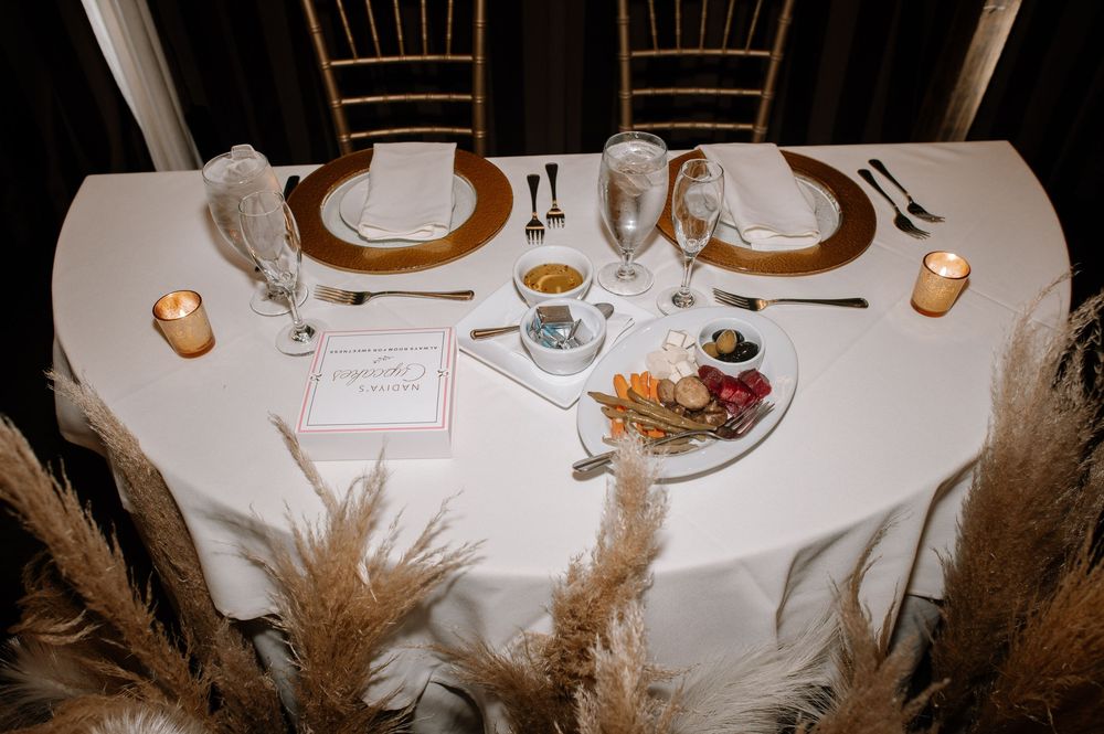 White table settings with dried pampas grass decorations create an elegant wedding reception atmosphere.