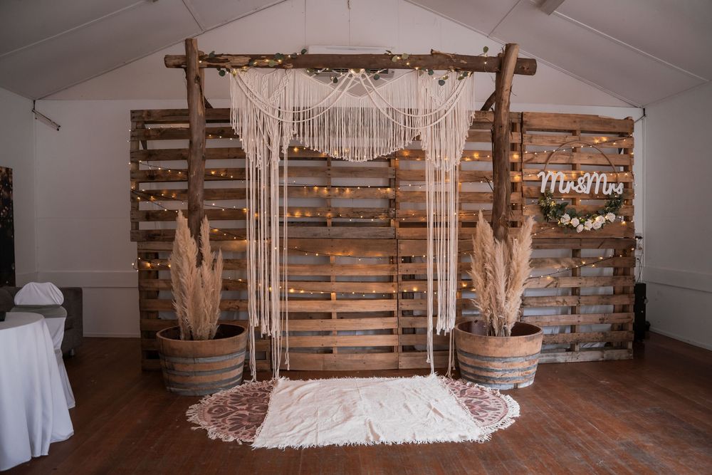 Rustic barn venue interior with wooden pallet backdrop and draped curtains for wedding ceremonies or photo sessions.