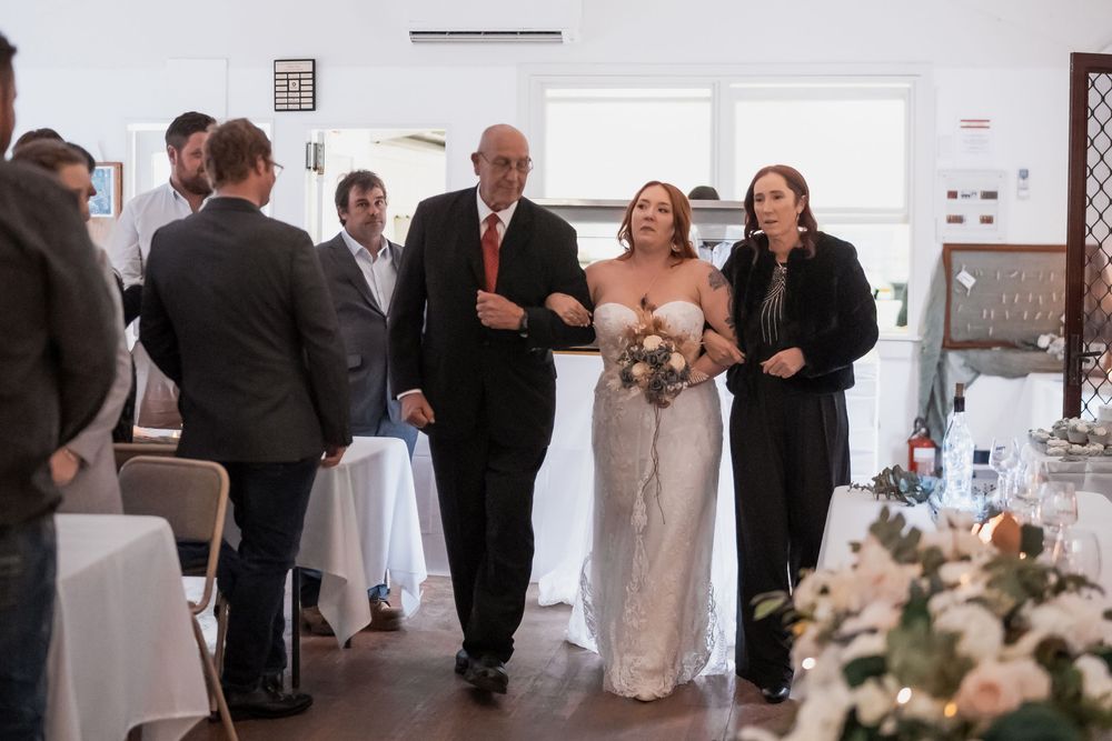 An indoor wedding celebration at an elegant venue with floral centerpieces and white tablecloths.