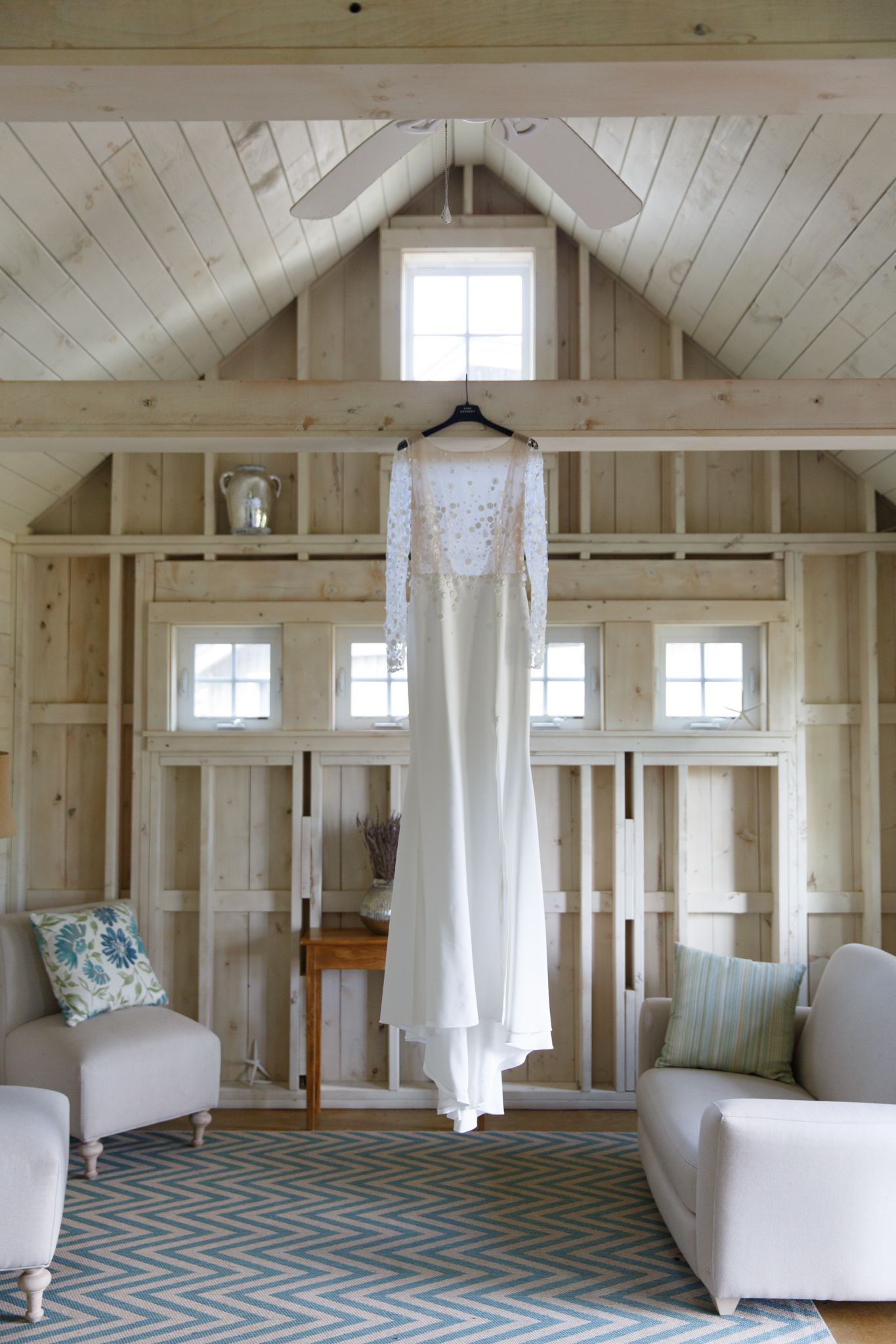 Bright white interior of a barn venue with chevron carpet and sheer curtains.