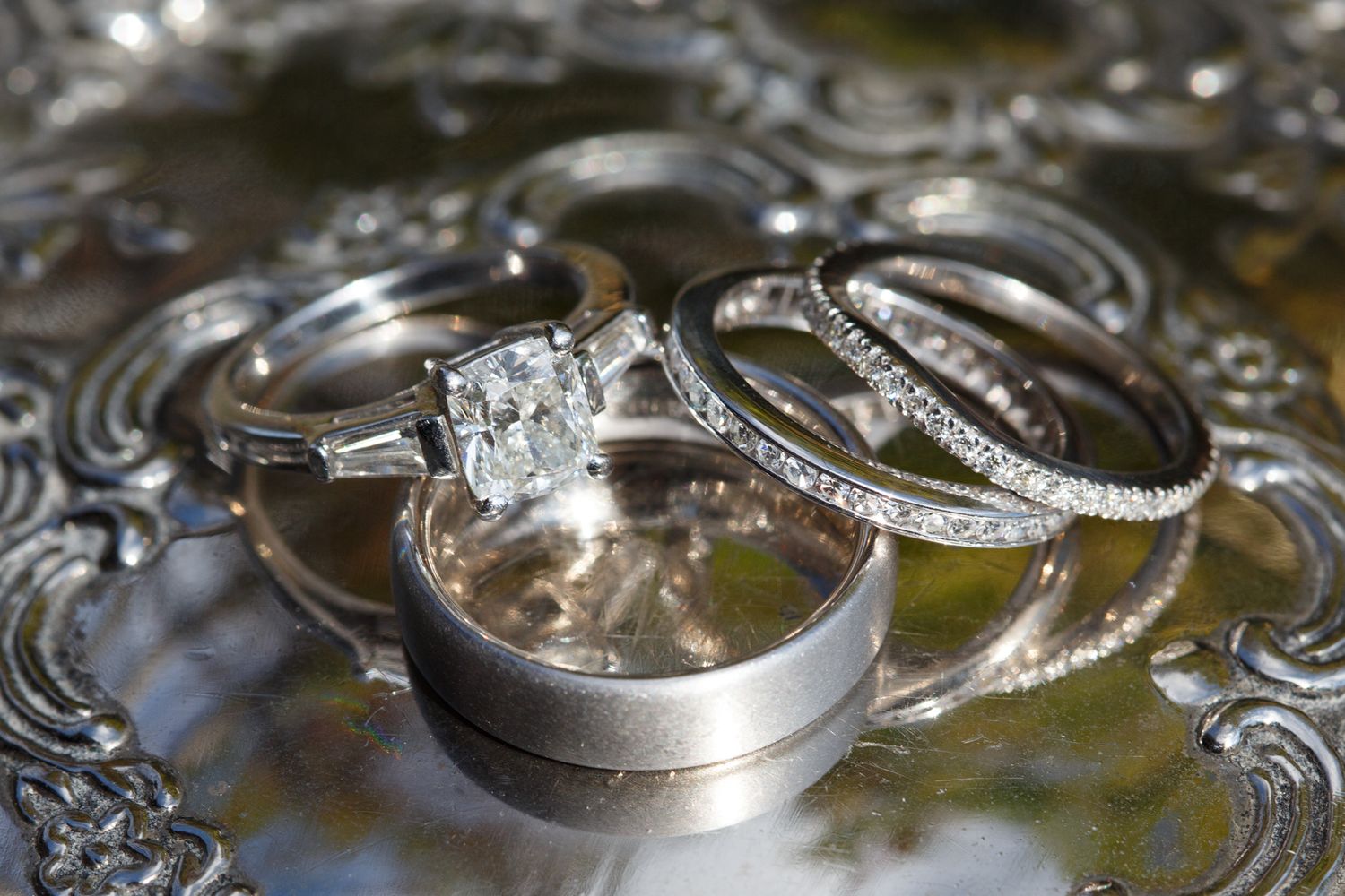 Close-up details of silver wedding rings on an ornate metallic surface.