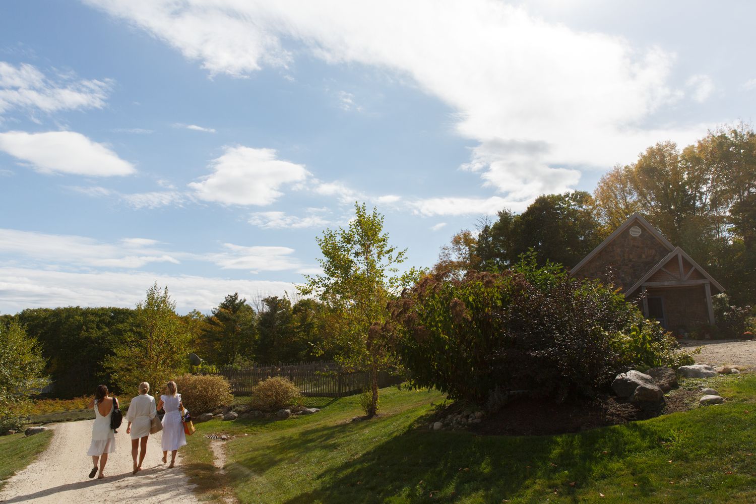 Panoramic view of people walking along a hilltop path under blue skies.
