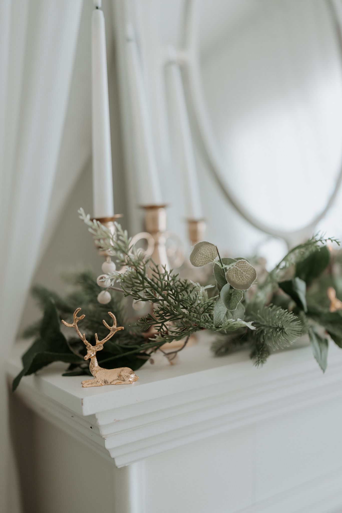 Frosted artificial Christmas tree with snow-covered branches creates a serene winter wonderland aesthetic against white curtains.