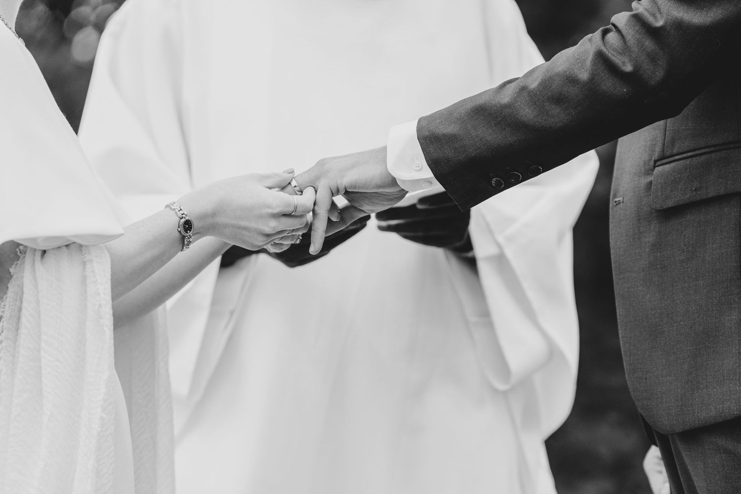 Wedding ceremony moment showing close-up of couple exchanging rings at the altar.