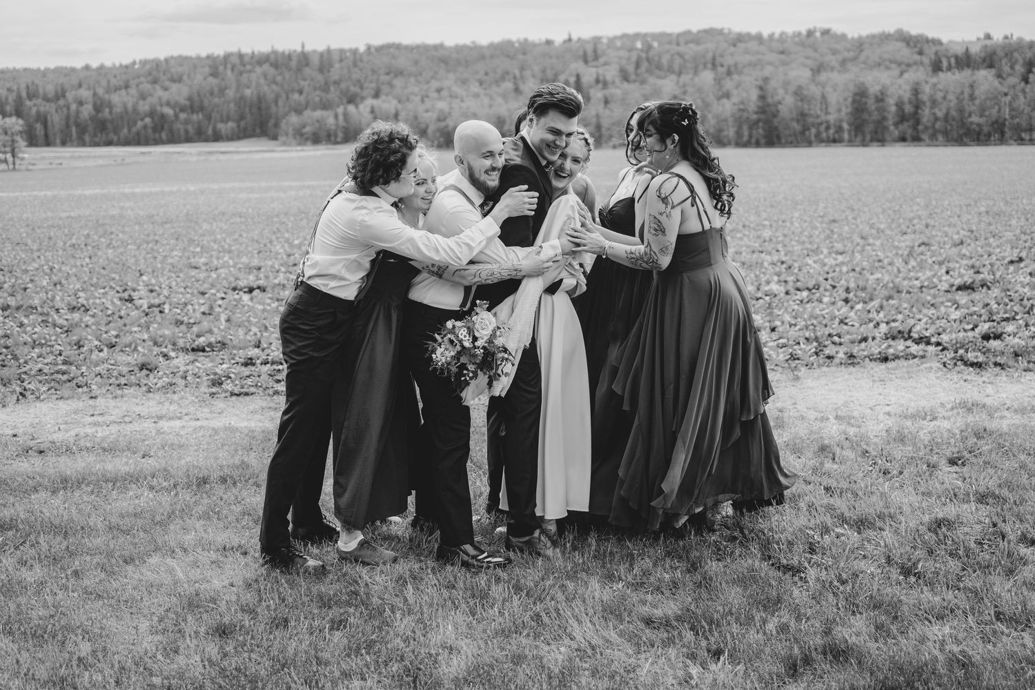 A candid black and white photo of wedding guests sharing an intimate moment in a field.