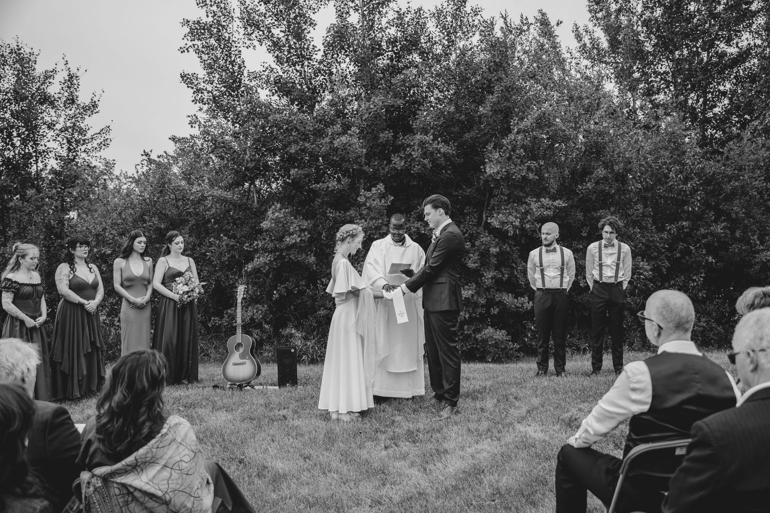 Black and white outdoor ceremony photographs showing a line of attendees in formal wear among trees.