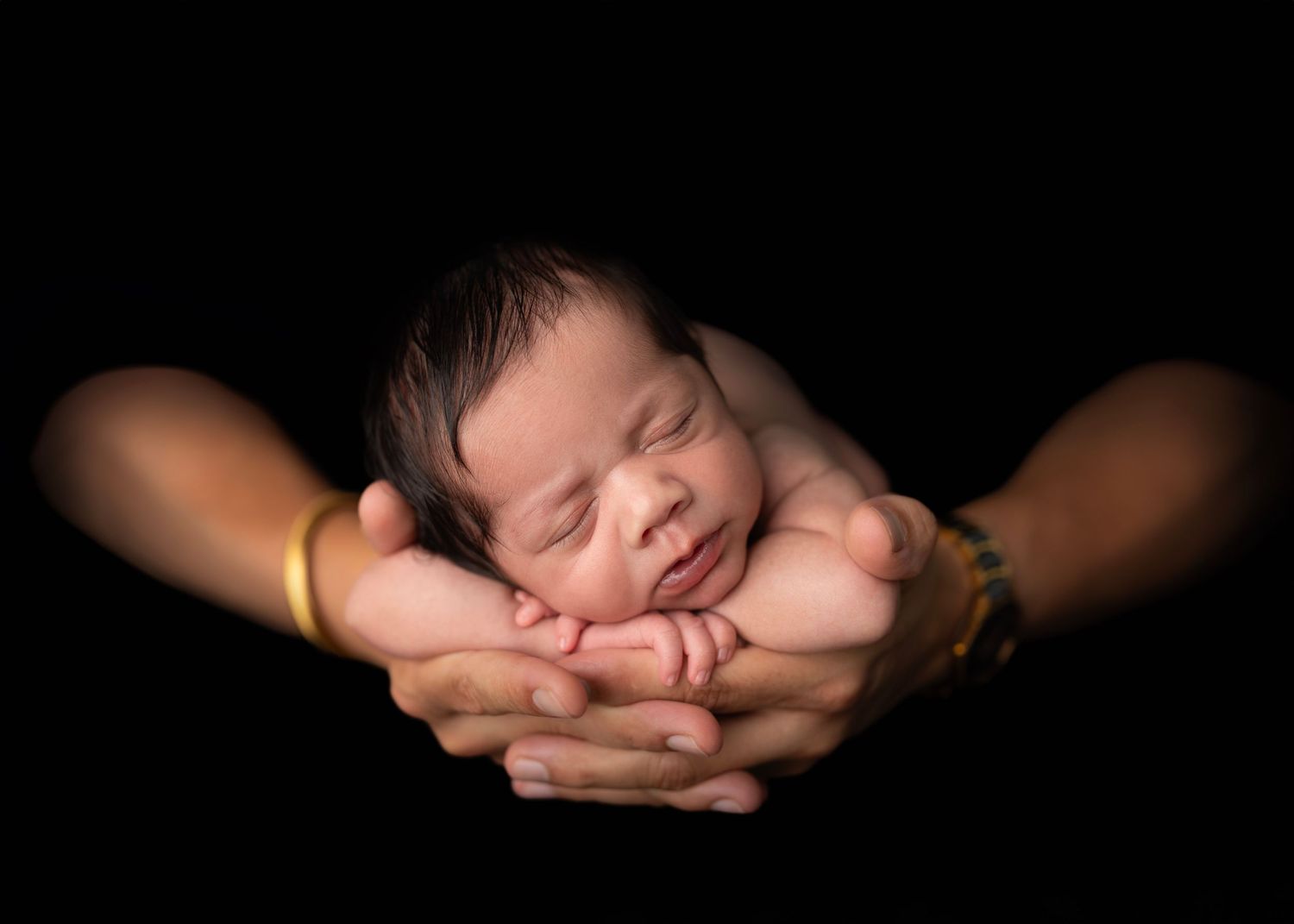 newborn photography dad holds hands together to cradle his newborn son.