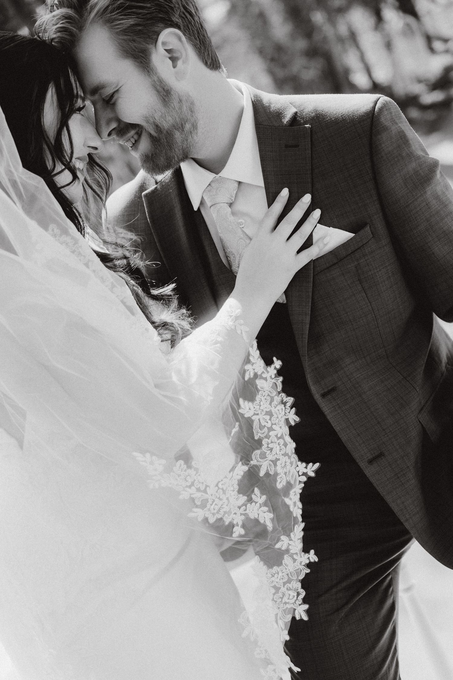 Bride and groom in a close black-and-white portrait with lace and veil.