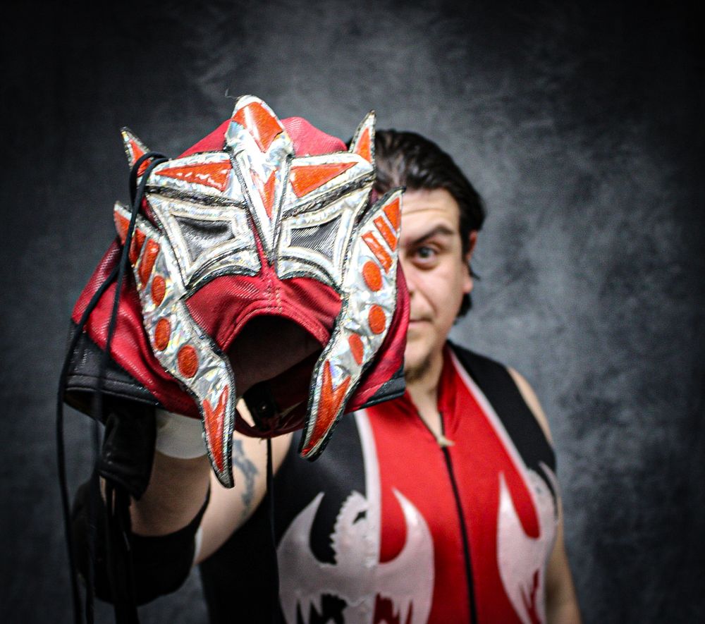 Professional wrestling face mask with red and white designs shown from multiple dramatic angles.
