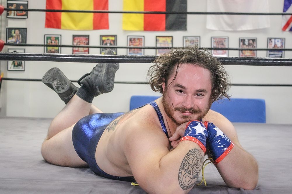 Wrestlers competing on a mat during an intense match with indoor arena lighting.